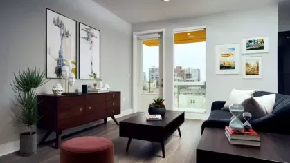 Beautifully designed living room at The Linden Luxury Apartments with large windows, eclectic decor, and a view of the city skyline.