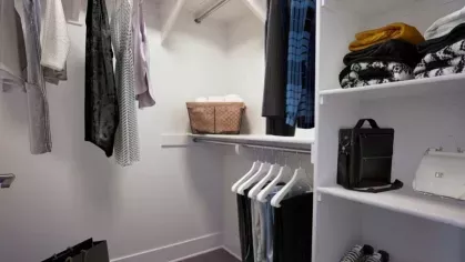 Spacious walk-in closet at The Linden Luxury Apartments with ample shelving and hanging space, showcasing organized clothing and accessories.