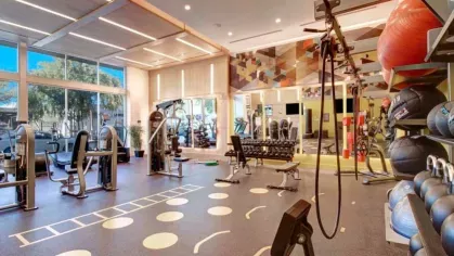 Expansive fitness area at The Linden Luxury Apartments with weight machines, functional training equipment, and a colorful, artistic design.