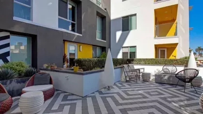Modern outdoor courtyard at The Linden Luxury Apartments featuring stylish seating, vibrant yellow accents, and geometric tile flooring