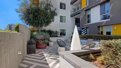 "Contemporary patio space at The Linden Luxury Apartments with lush greenery, artistic architecture, and cozy seating areas"