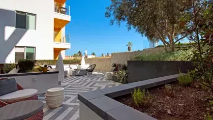 "Serene outdoor lounge area with patterned tiles, shaded seating, and natural greenery at The Linden Luxury Apartments"