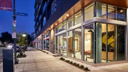 "Street view of The Linden Luxury Apartments with illuminated interiors and a colorful mural on the adjacent wall"