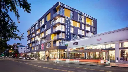 "Corner view of The Linden Luxury Apartments with modern architectural design and neighboring Berlin café"