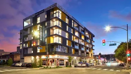 "Nighttime street view of The Linden Luxury Apartments showcasing contemporary design, illuminated signage, and bustling city vibes"