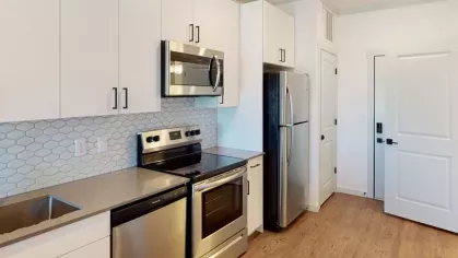 Bright and airy kitchen with white cabinetry, stainless steel appliances, and a beautiful hexagonal tile backsplash at The Prospector Modern Luxury Apartments.