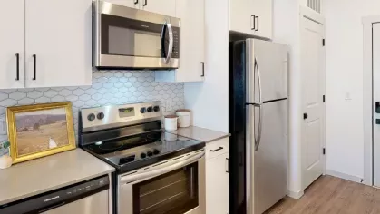 Modern kitchen with ample storage, a double-door refrigerator, and a stylish combination of white and stainless steel finishes at The Prospector Modern Luxury Apartments.