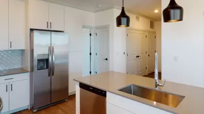 Spacious kitchen with modern white cabinets, stainless steel appliances, and a minimalist design at The Prospector Modern Luxury Apartments.