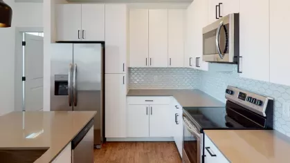 Well-designed open floor plan with a kitchen island, modern light fixtures, and a welcoming living space at The Prospector Modern Luxury Apartments.