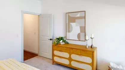 Bedroom view showcasing a mid-century modern dresser, abstract wall art, and tasteful greenery for a fresh, inviting ambiance.