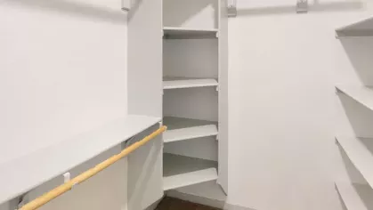 Large walk-in closet with built-in shelving and rods, providing generous storage and organization options.