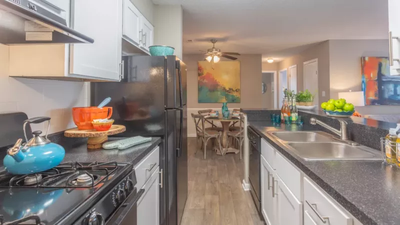 Stylish kitchen with black appliances, white cabinetry, and colorful decor.