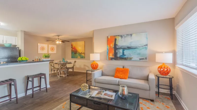 Bright living room with modern art, orange accents, and an open floor plan.
