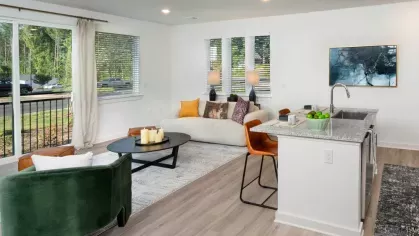 Bright living room with large windows, a green accent chair, and an open-concept layout.