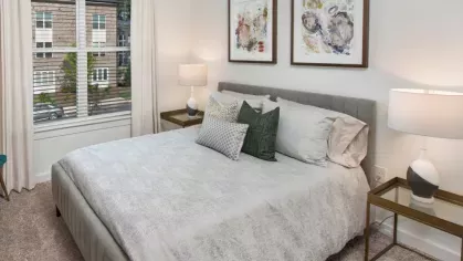 Elegant bedroom with soft carpeting, white bedding, and decorative framed art on the wall.
