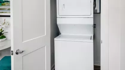 A laundry nook with a white stacked washer and dryer, neatly tucked behind double doors.