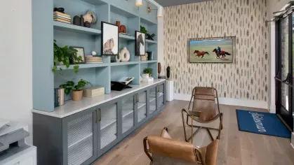 A chic workspace with teal cabinetry, decorative items, and leather chairs under a bold blue ceiling.