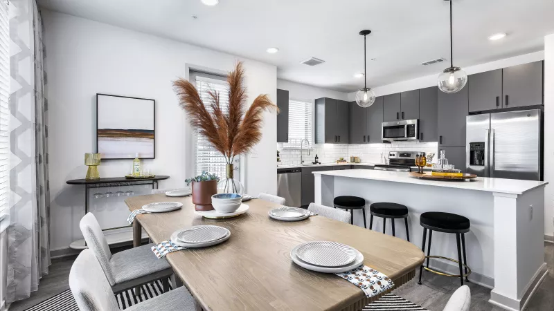 A contemporary living area featuring a plush sectional, stylish accent chairs, and a kitchen with an island in the background.