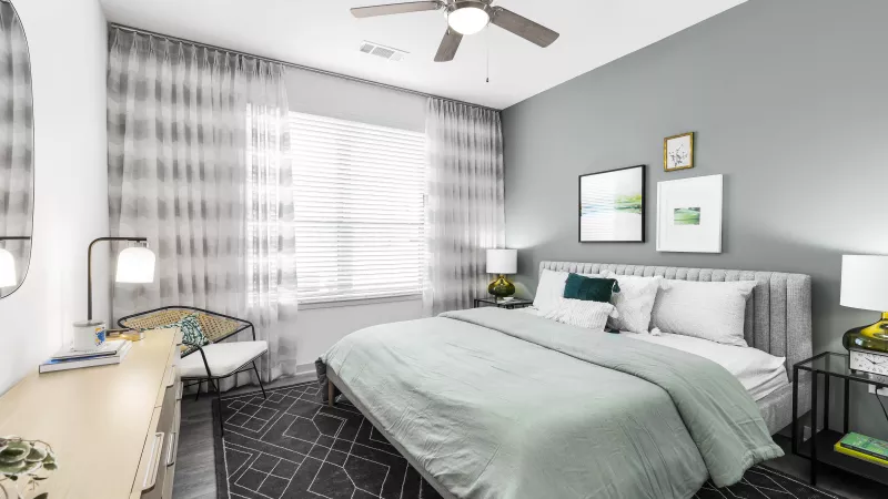 A bright and inviting bedroom with a tufted headboard, soft green bedding, and elegant wall art, creating a peaceful retreat.