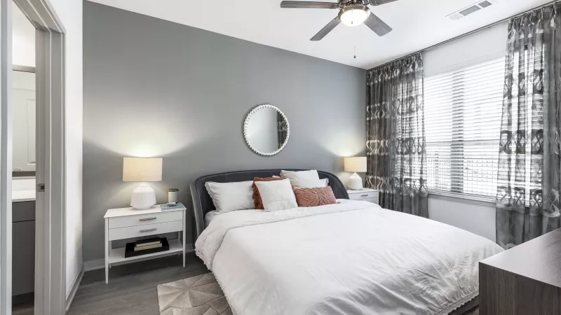 A bright and inviting bedroom with a tufted headboard, soft green bedding, and elegant wall art, creating a peaceful retreat.