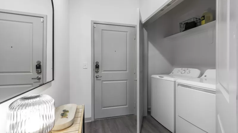 A convenient in-unit laundry space with a stacked washer and dryer, built-in shelving, and sleek modern finishes.