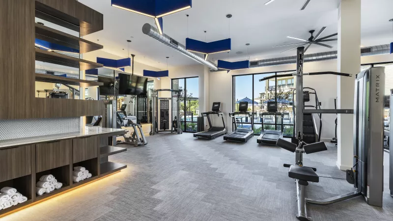 A bright and spacious gym with treadmills, weight machines, and large windows that overlook the pool area for an energizing workout experience.