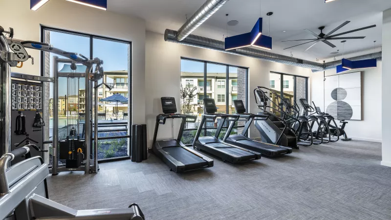 A bright and spacious gym with treadmills, weight machines, and large windows that overlook the pool area for an energizing workout experience.