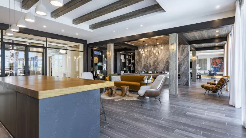 A stylish resident lounge with modern industrial touches, a large communal table, and a cozy seating area designed for relaxation and socializing.