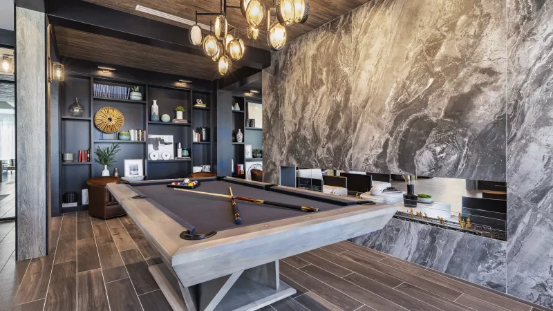 A stylish lounge area with a pool table, open shelving, plush seating, and contemporary lighting, creating a warm and inviting space for residents.