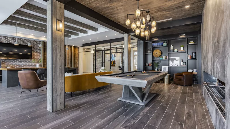 A stylish lounge area with a pool table, open shelving, plush seating, and contemporary lighting, creating a warm and inviting space for residents.