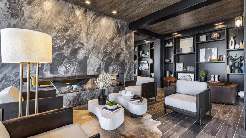 A sophisticated private dining or meeting space at The Warner Apartments, showcasing a bold abstract painting, a statement chandelier, and a chic round dining table with plush chairs.