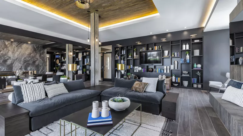 A contemporary co-working space at The Warner Apartments with a mix of soft seating, communal work tables, and floor-to-ceiling windows allowing for natural light and an open, airy feel.