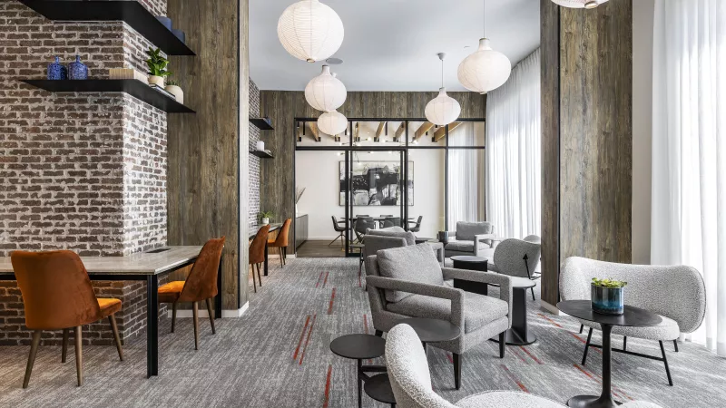 The Warner Apartments’ welcoming reception area, boasting a stylish concrete and wood desk, textured accent walls, and modern pendant lighting, creating a sophisticated first impression.