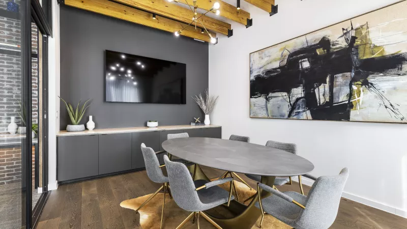 The Warner Apartments' clubhouse with floor-to-ceiling windows, offering a view of the outdoor pool area, complemented by dark sofas, gold-accented lighting, and a warm, contemporary aesthetic.