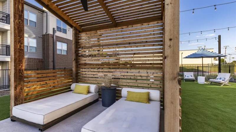 Slatted wood walls create a semi-private space, featuring plush seating and a ceiling fan for added comfort.