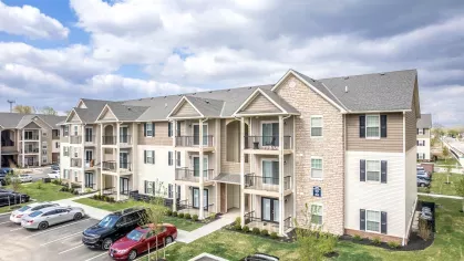 A front view of the apartment complex highlighting multiple units, parking, and a beautifully landscaped walkway.
