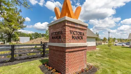 Brick monument with the Victoria Manor logo surrounded by landscaping, welcoming residents and visitors to the luxury apartment community.