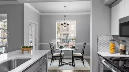 A bright kitchen with stainless steel appliances, white cabinetry, and a cozy dining area with natural light.