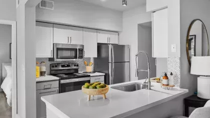 A modern kitchen with stainless steel appliances, a sleek island, and comfortable seating for two.