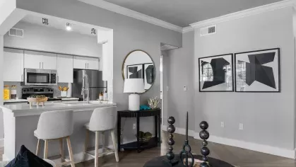 A contemporary living area with a white sofa, black coffee table, and an open view of the kitchen.