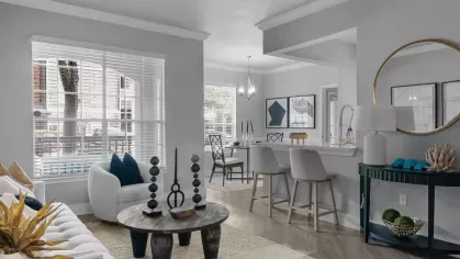 A light-filled living room with elegant decor, large windows, and a seamless flow into the kitchen area.