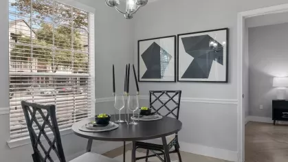 A charming dining area with a black round table, stylish chairs, and natural light from a large window.
