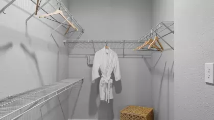 A spacious walk-in closet with ample shelving, hangers, and a neatly placed robe.