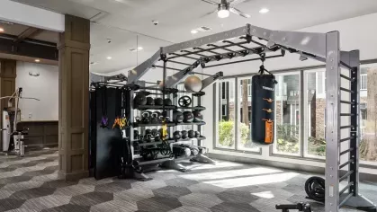 A modern gym featuring strength training equipment, including a full workout station and free weights.