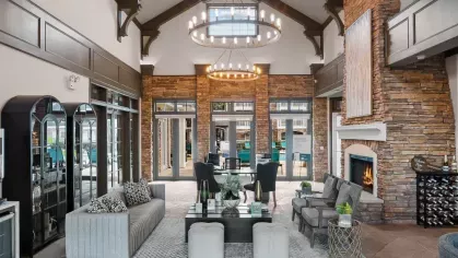 A luxurious clubhouse with high vaulted ceilings, a grand stone fireplace, and elegant seating arrangements.