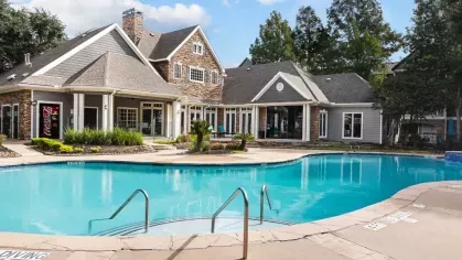 A large community pool with stone accents and a clubhouse with classic architectural design.