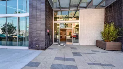 "Modern entrance of The Pacific Luxury Apartments featuring sleek glass doors, contemporary architecture, and landscaped greenery, offering a welcoming first impression."