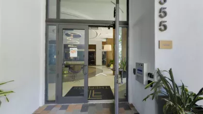 Welcoming entrance to The Flats at City Place Luxury Apartments, featuring modern glass doors, stylish interior decor, and the property's signature logo for a sophisticated first impression.