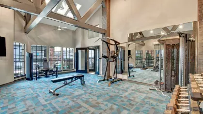 Fitness center with vaulted ceilings, skylights, weight training machines, and ample natural light