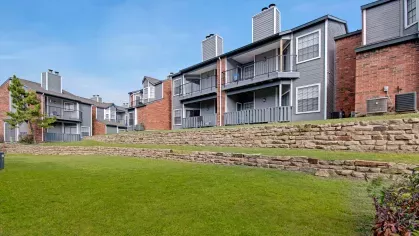 Terraced landscaping with stacked stone walls in front of apartment buildings with balconies